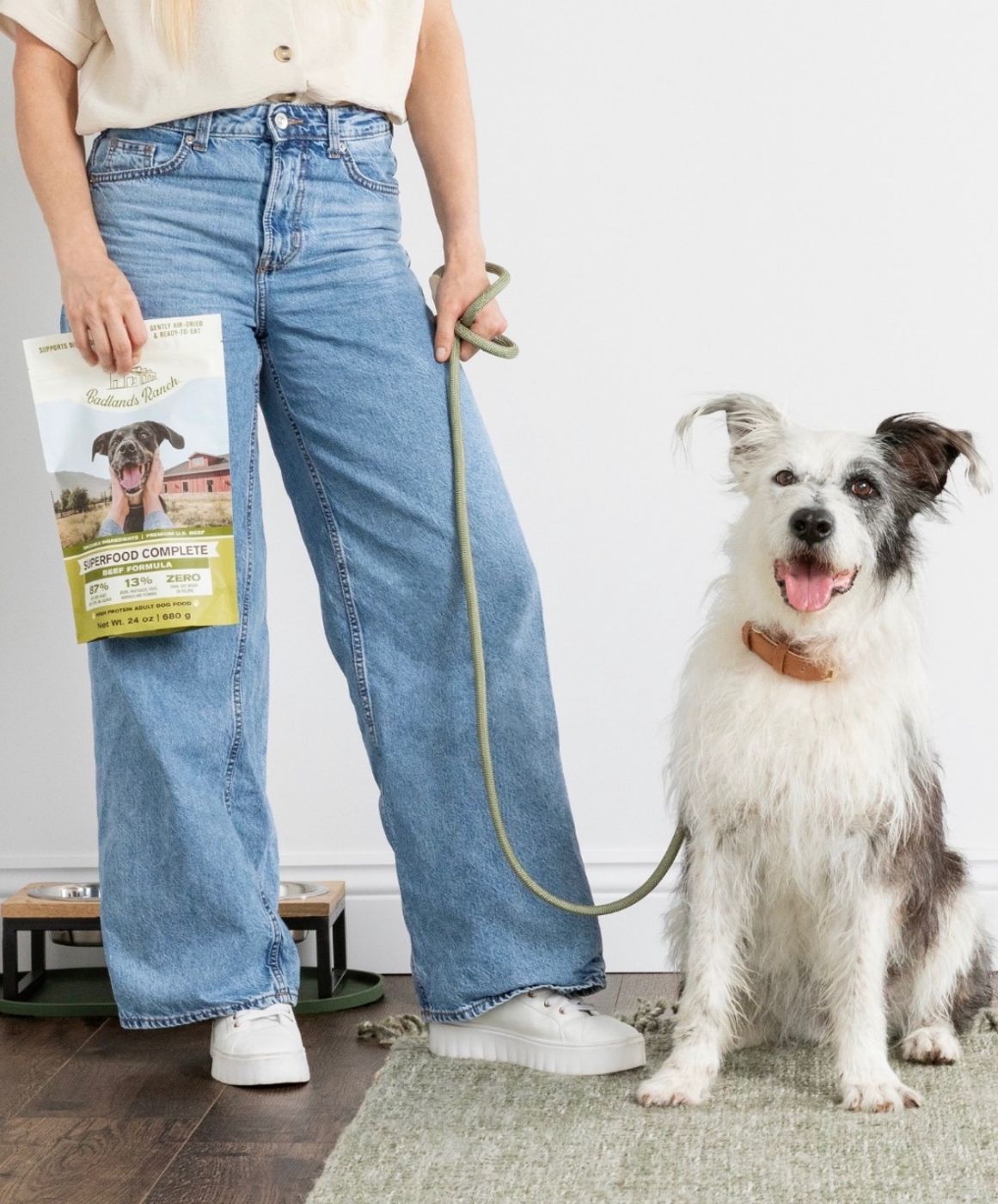 Dog on a leash beside its owner holding a bag of natural dog food from Earthwise Pet South Lamar